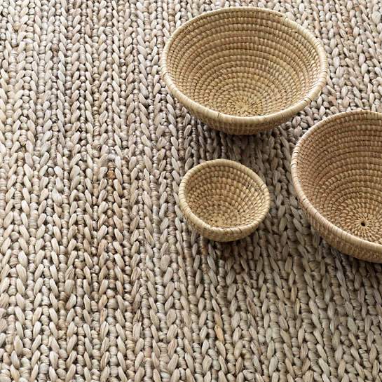 Jute Woven Seaglass Rug styled under woven bowls. Styled view. 