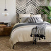 Kali Woven Jute Rug styled in a black and white bedroom. Styled view. 
