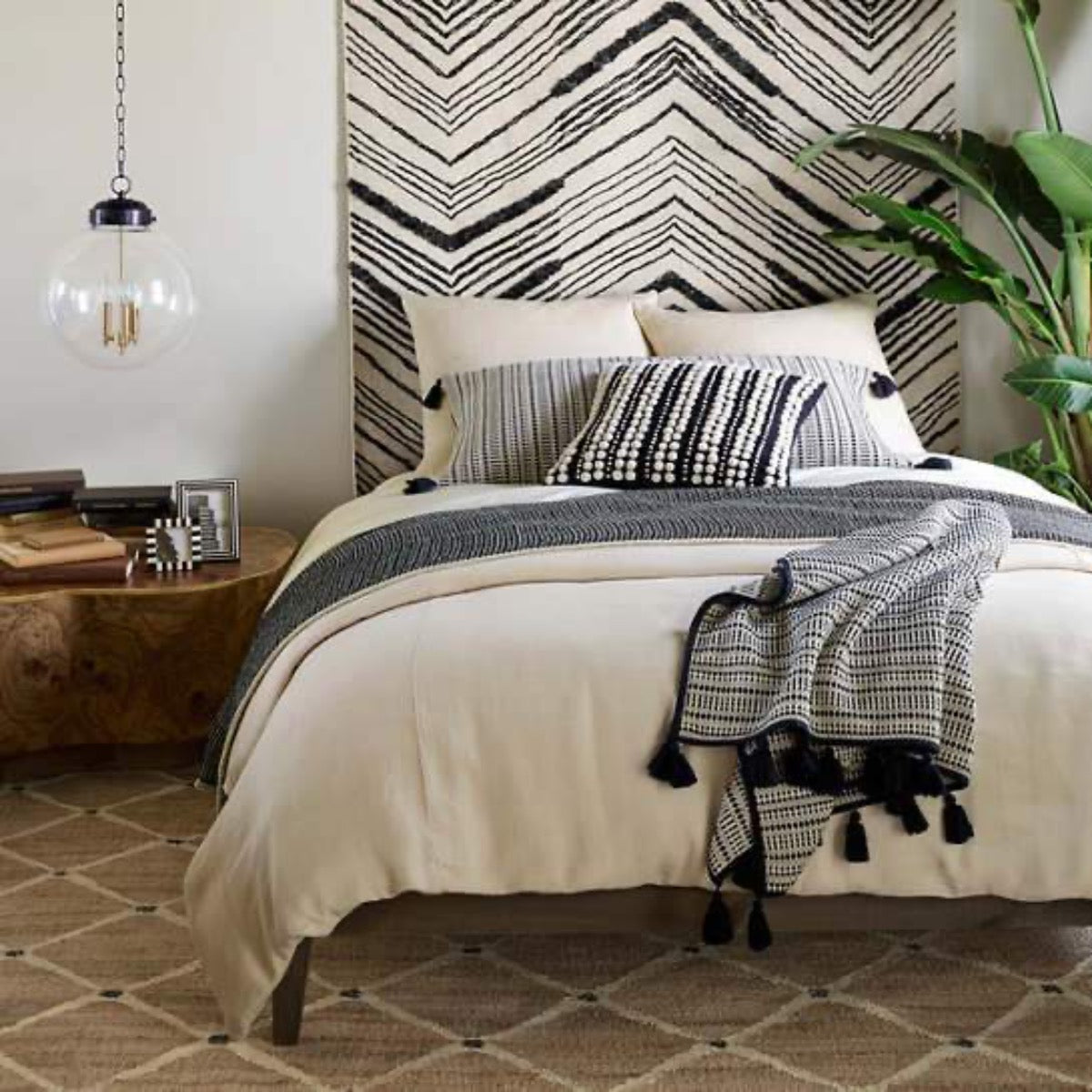 Kali Woven Jute Rug styled in a black and white bedroom. Styled view. 