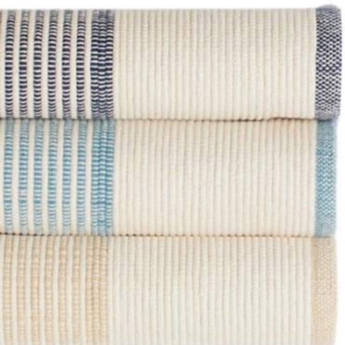 La Mirada Wheat Woven Cotton Rug styled with striped rugs. Styled view.