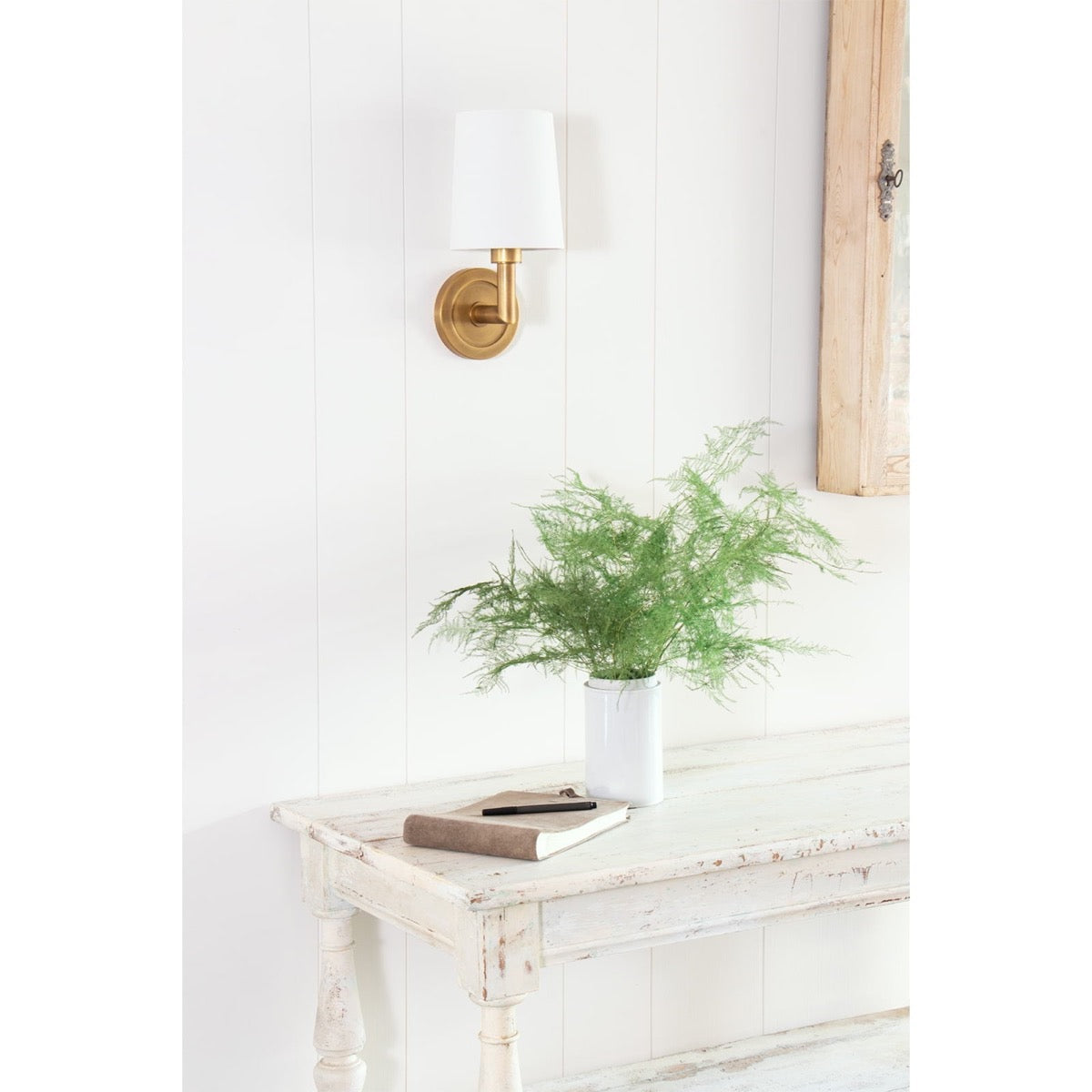 Legend Single Sconce styled over a white table with greenery. Styled view.