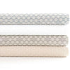 Folded stack of coverlets in multiple colours. Styled view.