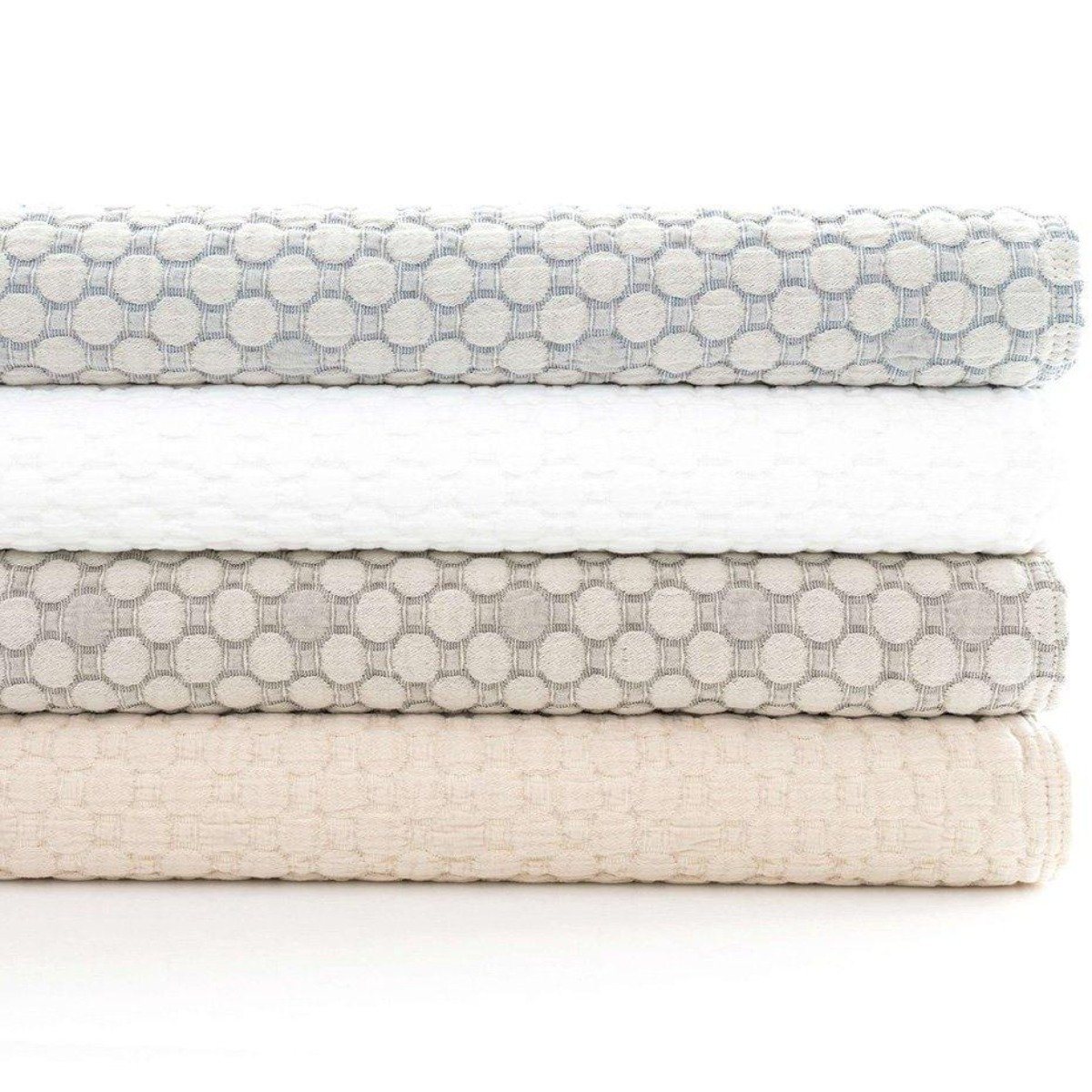 Folded stack of coverlets in multiple colours. Styled view.