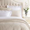 Lodi Alabaster Matelasse Coverlet styled on a neutral bed. Styled view. 