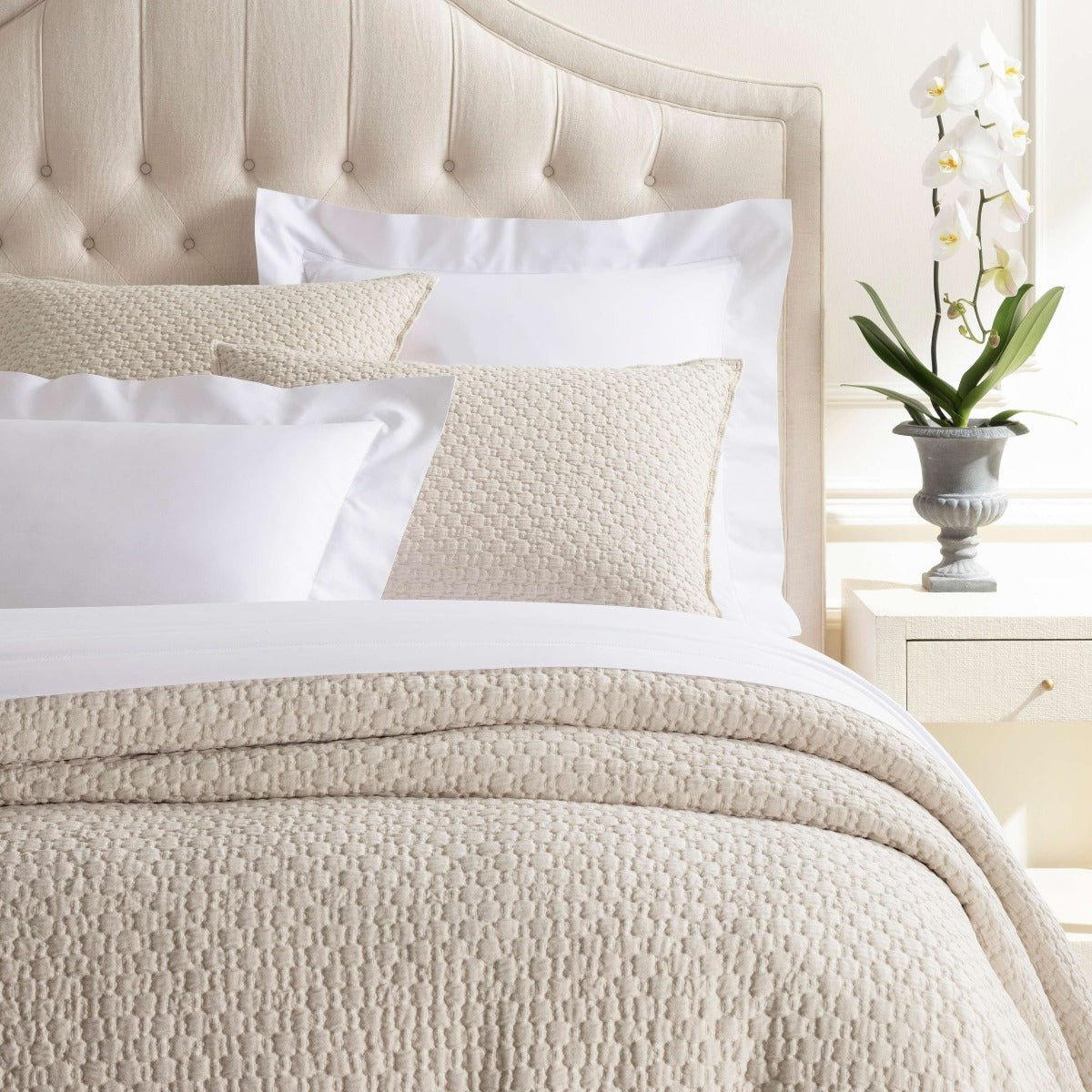 Lodi Alabaster Matelasse Coverlet styled on a neutral bed. Styled view. 