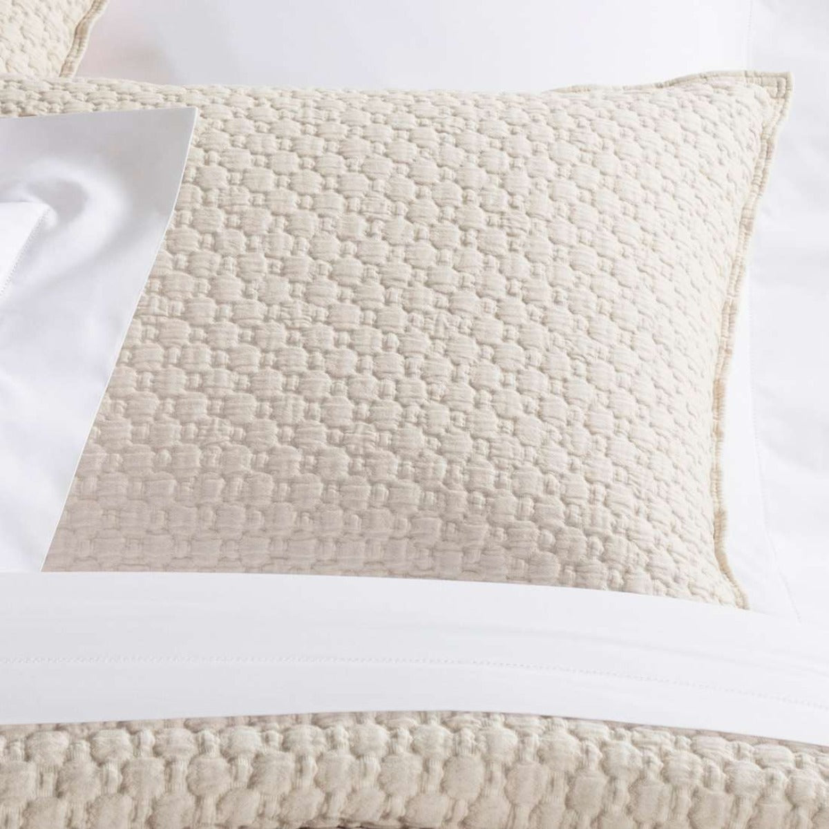 Lodi Alabaster Matelasse Sham styled with white sheets. Styled view.