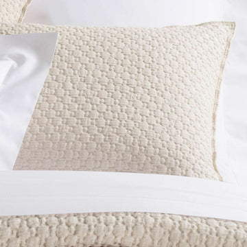 Lodi Alabaster Matelasse Sham styled with white sheets. Styled view.