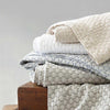 Folded stack of coverlets in multiple colours. Styled view.
