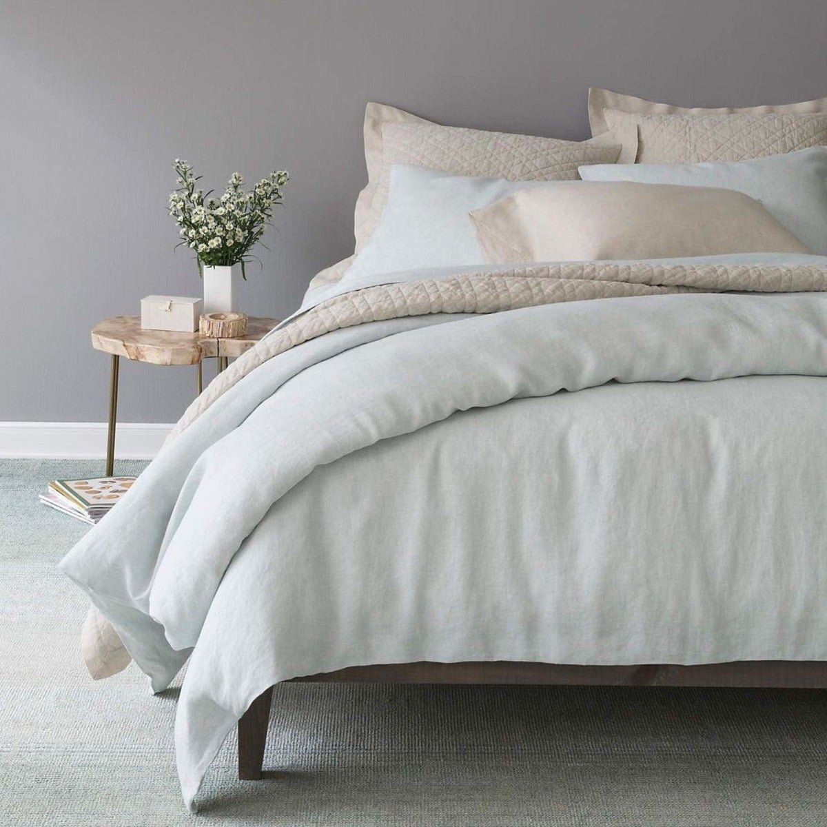 Lush linen bedding in the colour sky with neutral sheets. Styled view.