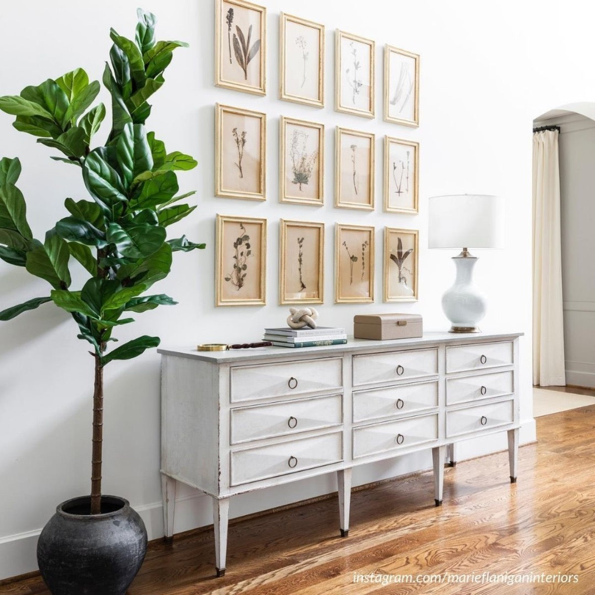 Marie White Table Lamp styled on a white dresser with a gallery wall. Styled view.