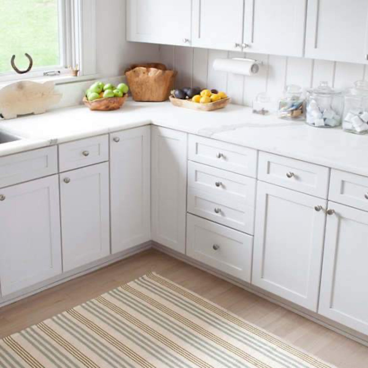 Olive Branch Woven Cotton Rug styled in a white kitchen. Styled view. 