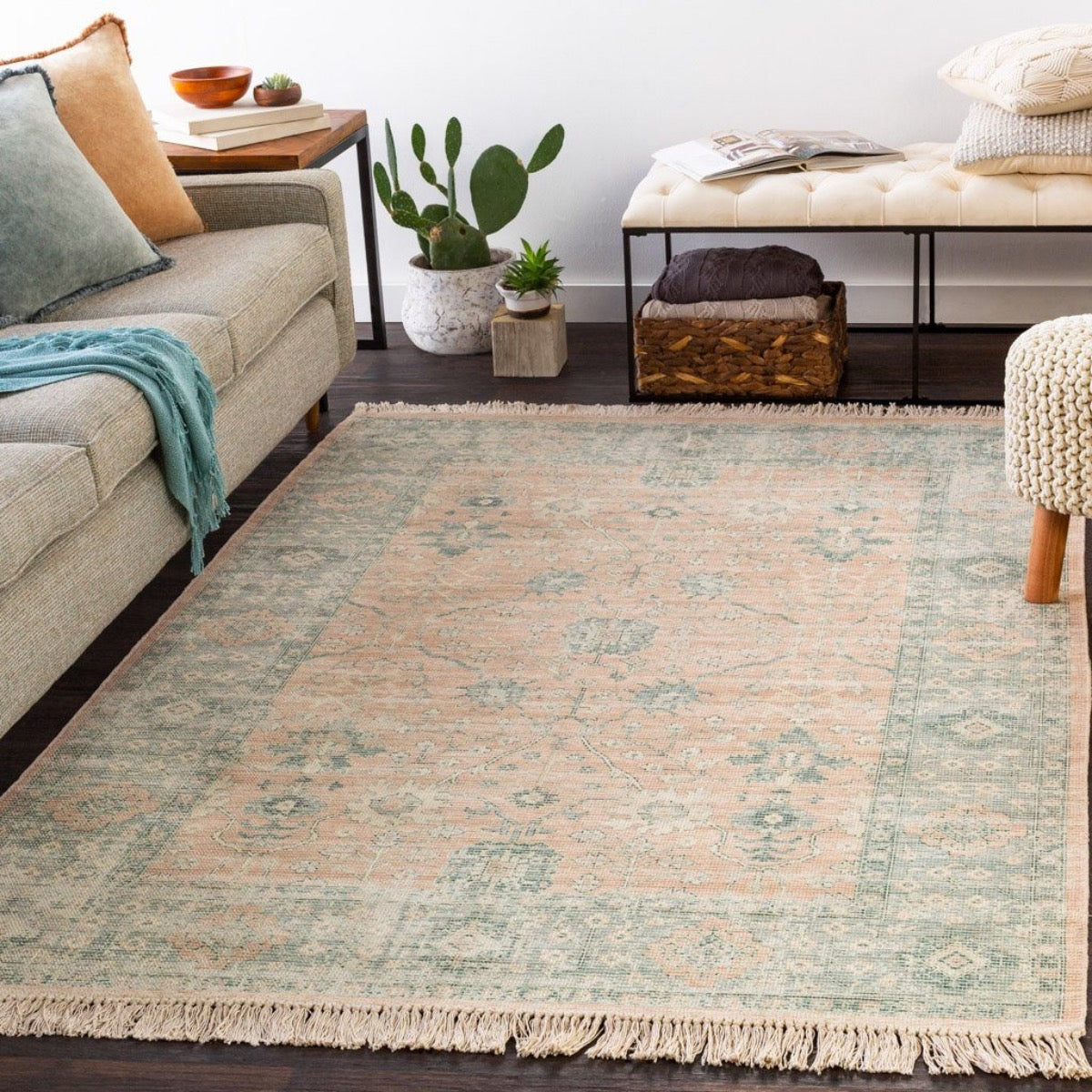 Ollie Rug styled with a grey sofa, neutral stool and greenery. Styled view. 