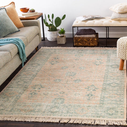 Ollie Rug styled with a grey sofa, neutral stool and greenery. Styled view. 
