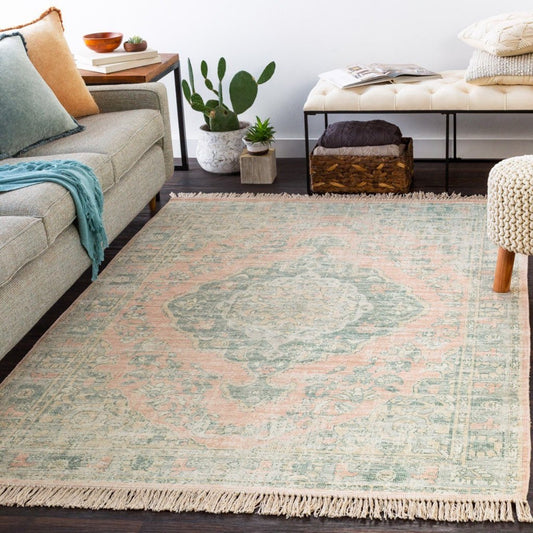 Perry Rug styled with a grey sofa, neutral stool and greenery. Styled view. 