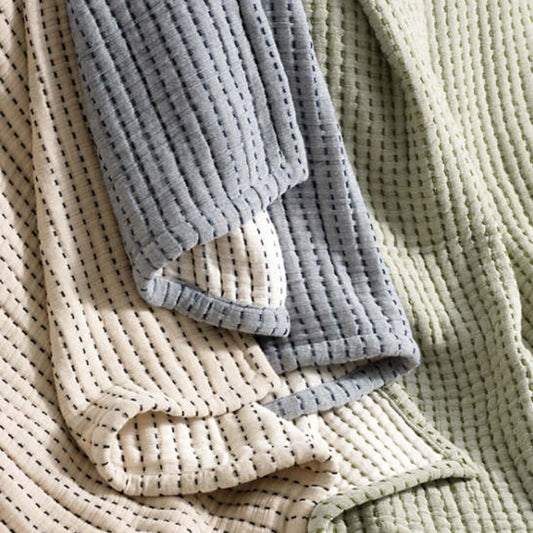 Pick stitch bedding in green, blue and cream. Styled view.