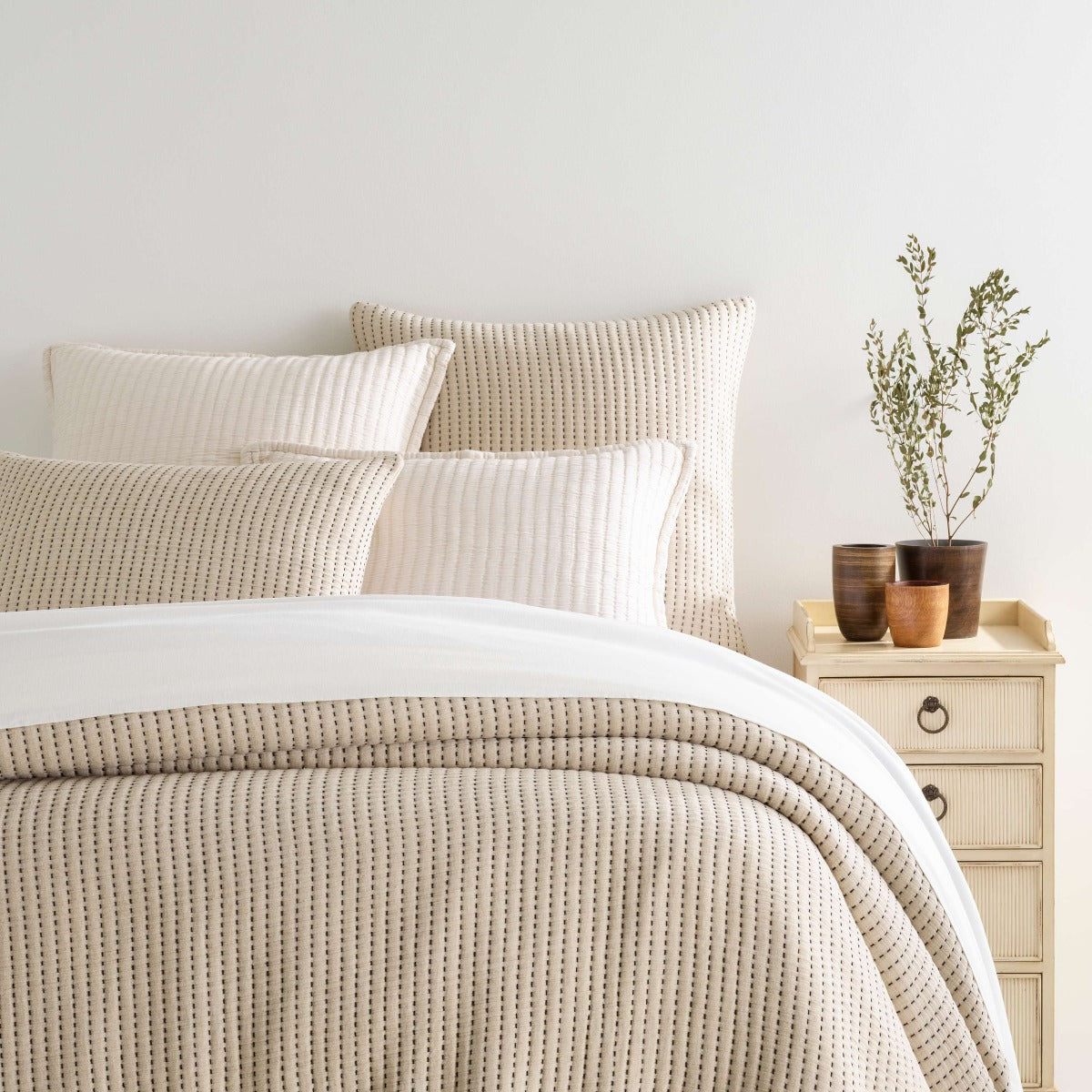 Pick Stitch Natural Matelasse Coverlet styled with white sheets. Styled view. 