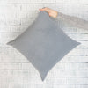 Royal Velvet Pillow - Dove Grey against a white brick wall. Styled view. 