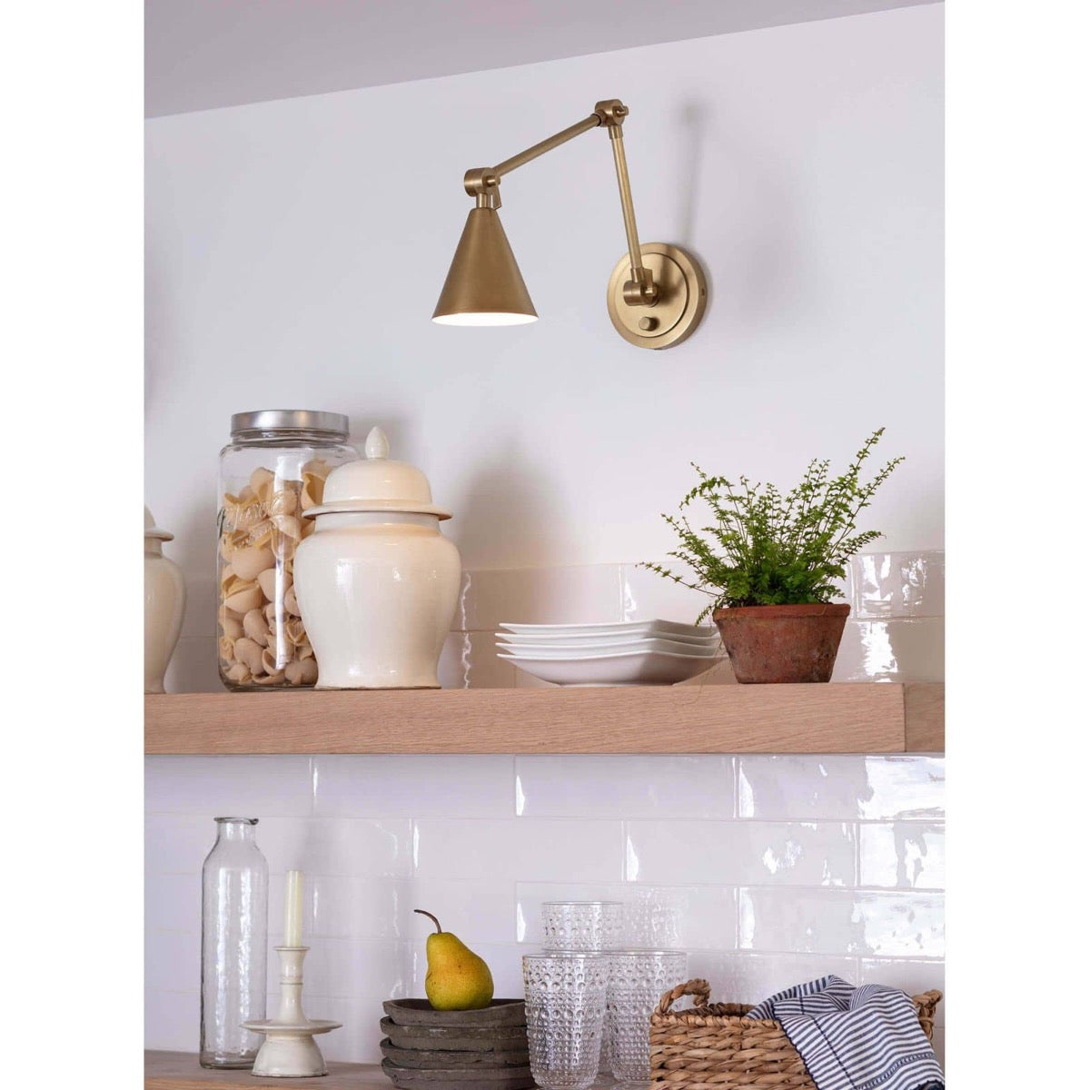 Sal Task Sconce Natural Brass styled over open kitchen shelving. Styled view.