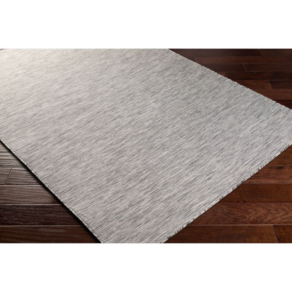 Seattle Grey Outdoor Rug styled over dark wood. Styled view.