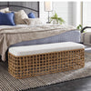 Sira Rattan Bench styled at the end of a blue and white bed with a brown rug. Styled view.