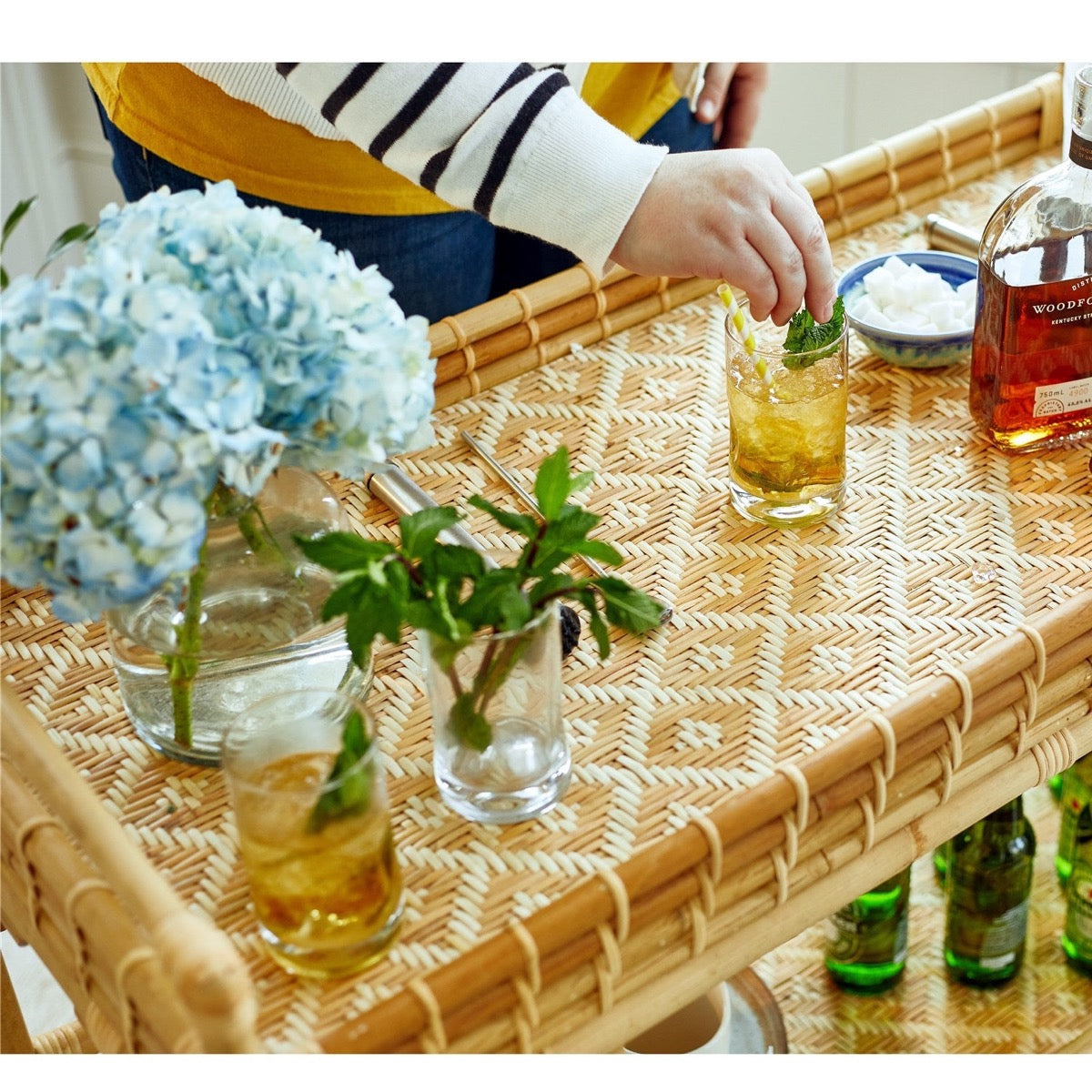 Tanner Rattan Bar Cart styled with glasses and blue florals. Styled view.
