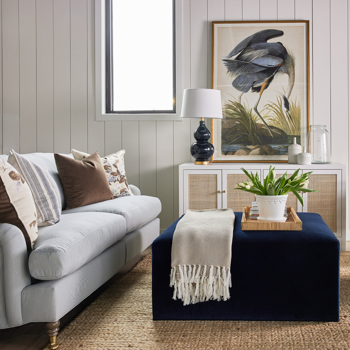 Thomas Block Ottoman styled with a blue sofa, jute rug and spring decor. Styled view. 