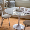 Trumpet Dining Table Round - Condo Size styled with white dining chairs and metal tray. Styled view.