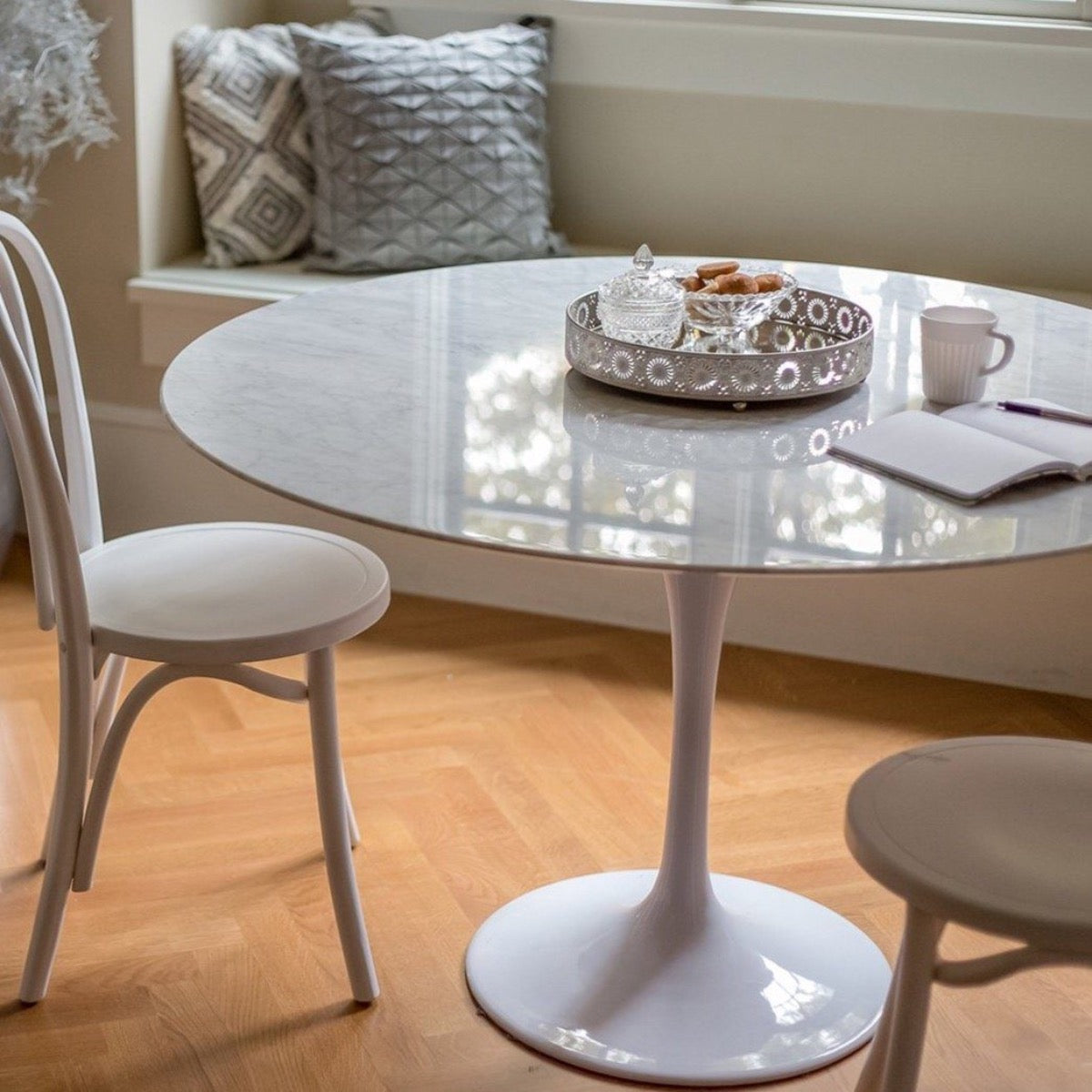 Trumpet Dining Table Round - Condo Size styled with white dining chairs and metal tray. Styled view.