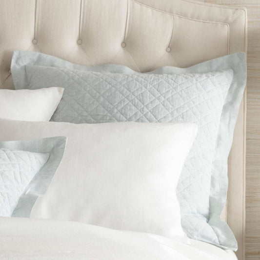 Washed Linen Sky Quilted Sham styled with white sheets. Styled view. 
