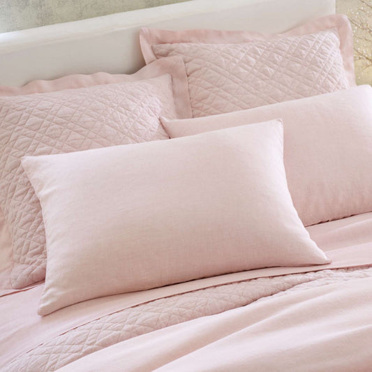 Close up of washed linen bedding in slipper pink. Styled view.