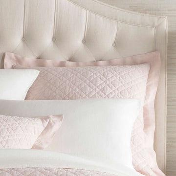 Washed Linen Slipper Pink Quilted Sham styled with white sheets. Styled view. 