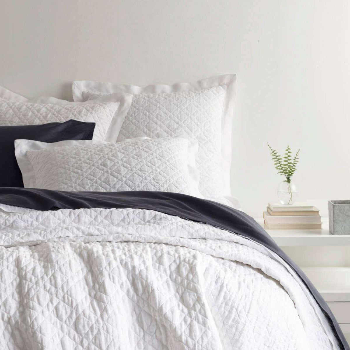 Washed Linen White Quilt styled with navy sheets. Styled view. 