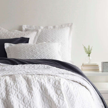 Washed Linen White Quilt styled with navy sheets. Styled view. 